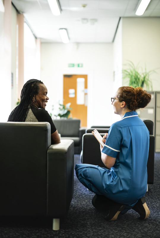 Nurse talking with patient in waiting area.