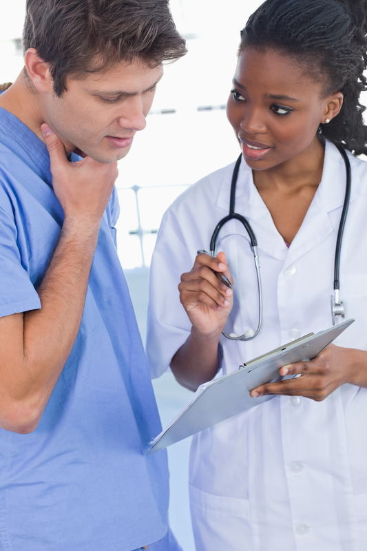 Doctors discussing over a clipboard in hospital.