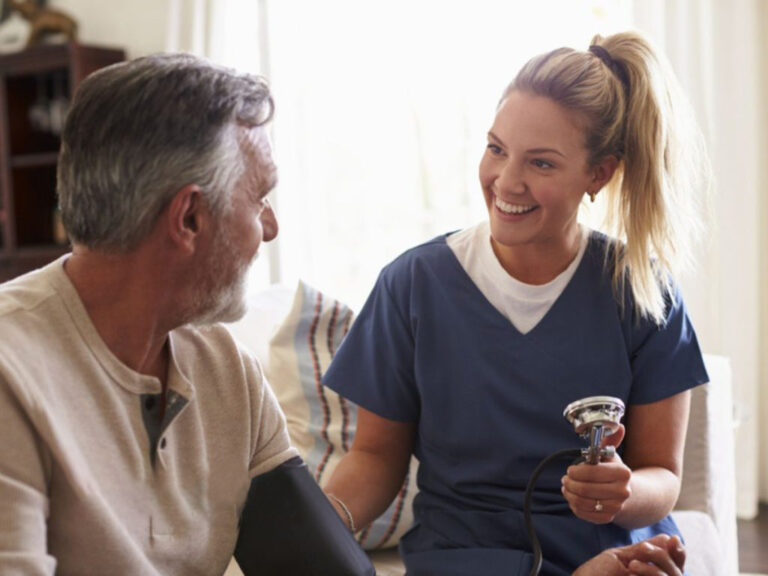 Nurse checking man's blood pressure at home.