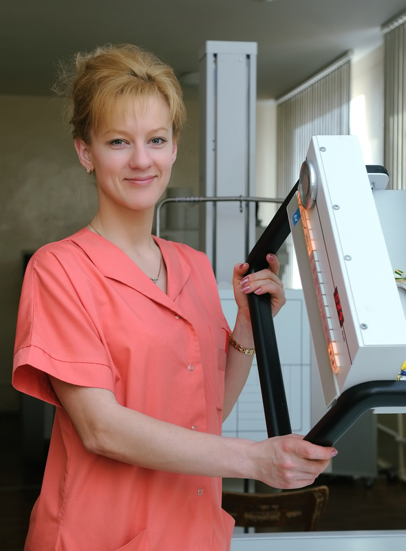 Smiling woman in medical uniform with equipment.