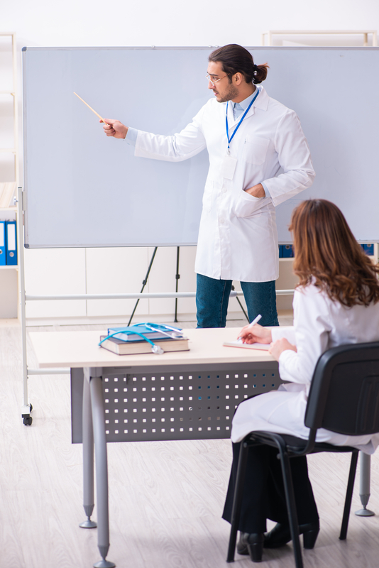 Man teaching woman in a lab coat.