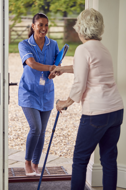 Nurse greeting elderly woman with handshake.