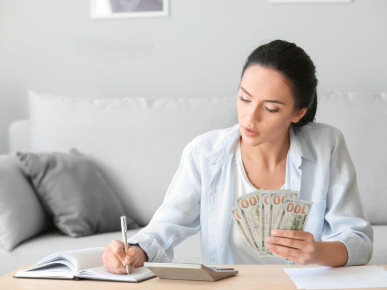 Woman calculating finances with cash and notebook.