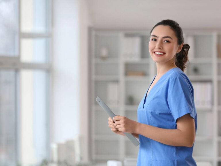 Smiling nurse holding a clipboard indoors.
